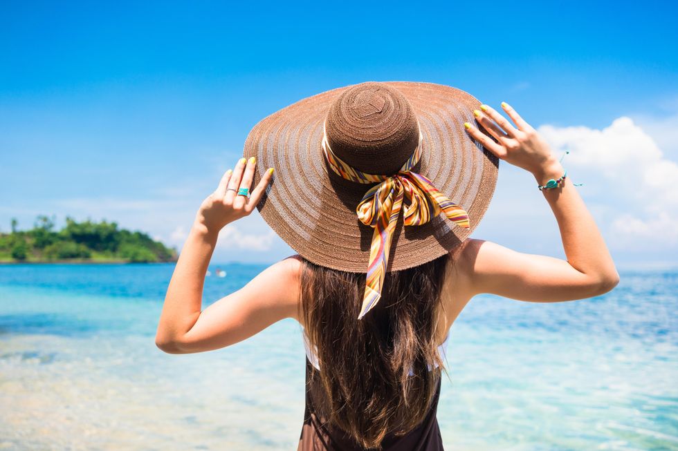 woman in hat looking at the beach